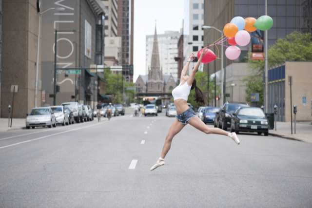 風船を持って大通りを踊って渡るダンサー