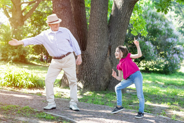 公園で踊る帽子の大人と子供